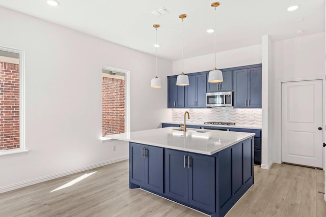 1126 Bexar Ln, Plano, TX 75075 - kitchen with appliances with stainless steel finishes, a sink, blue cabinetry, light wood-style floors, and recessed lighting