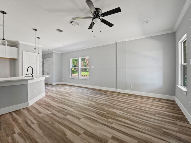 6223 Post Oak Ter, Fort Worth, TX 76112 - unfurnished living room featuring crown molding, ceiling fan, light wood-style floors, baseboards, and a sink