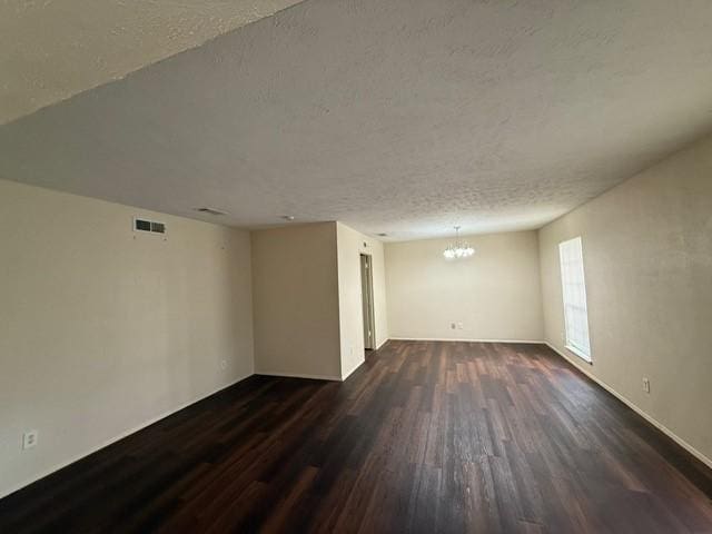 828 Wood Gln, Desoto, TX 75115 - empty room with dark wood-type flooring, a chandelier, a textured ceiling, and baseboards