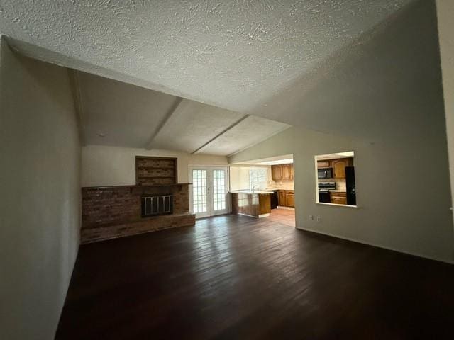 828 Wood Gln, Desoto, TX 75115 - unfurnished living room featuring dark wood finished floors, a brick fireplace, a textured ceiling, and vaulted ceiling