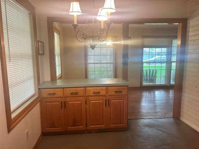 3415 Reily Ln, Shreveport, LA 71105 - kitchen with a chandelier, a peninsula, light countertops, pendant lighting, and brown cabinets
