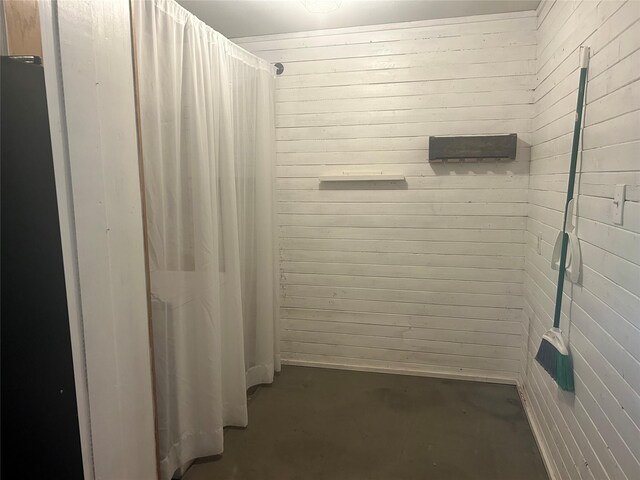 3415 Reily Ln, Shreveport, LA 71105 - bathroom with unfinished concrete flooring, curtained shower, and wood walls