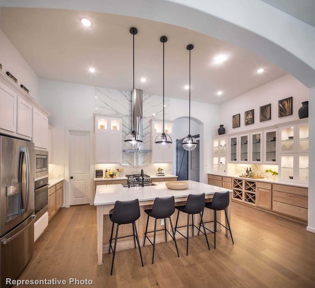 4621 Sandbrock Pkwy, Aubrey, TX 76227 - kitchen with appliances with stainless steel finishes, arched walkways, wall chimney range hood, backsplash, and light countertops