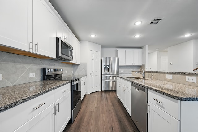 1611 Timpson Dr, Forney, TX 75126 - kitchen with appliances with stainless steel finishes, a sink, dark stone counters, white cabinetry, and decorative backsplash