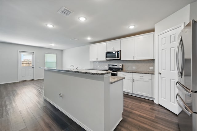 1611 Timpson Dr, Forney, TX 75126 - kitchen with stainless steel appliances, a center island with sink, tasteful backsplash, dark stone counters, and white cabinets