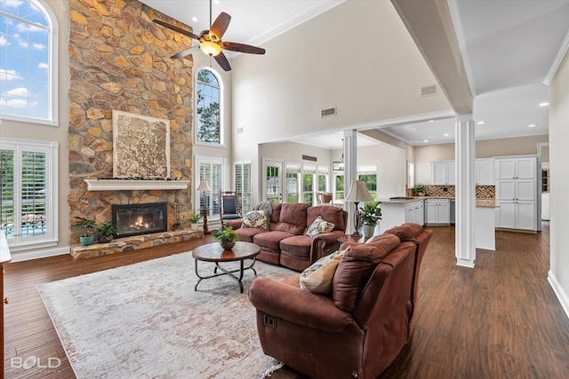 10198 Castanedo Ct, Keithville, LA 71047 - living area with ornate columns, ceiling fan, dark wood-style floors, a stone fireplace, and a high ceiling
