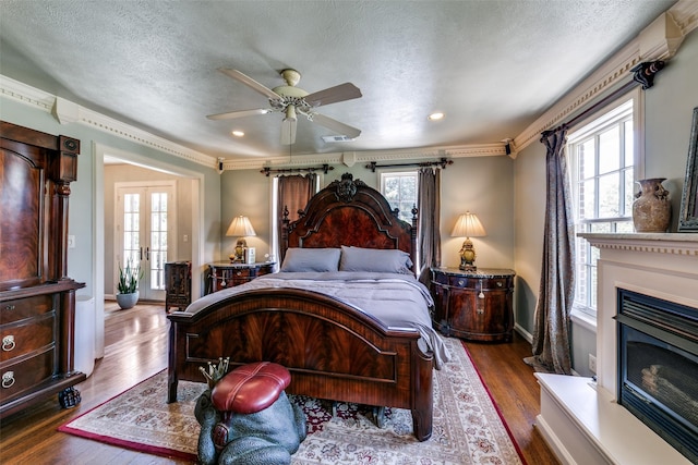 4317 Rawlins St, Dallas, TX 75219 - bedroom with wood finished floors, a glass covered fireplace, a textured ceiling, baseboards, and ceiling fan