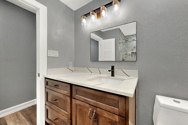 6912 Griggs St, Forest Hill, TX 76140 - bathroom with wood finished floors, toilet, baseboards, vanity, and a textured wall