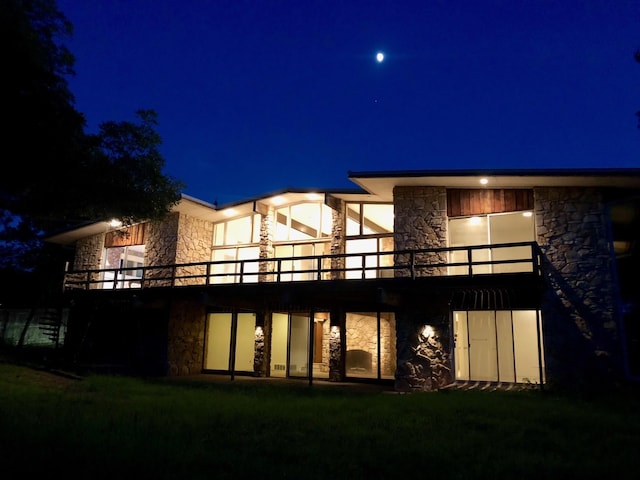 4208 Shore Front Dr, Fort Worth, TX 76135 - back of house at night with stone siding and a lawn