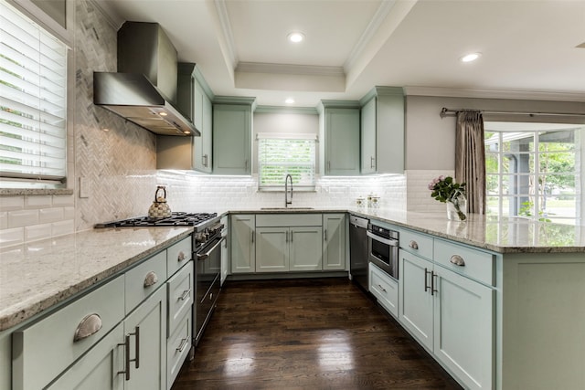 7514 Caillet St, Dallas, TX 75209 - kitchen featuring stainless steel appliances, wall chimney exhaust hood, a sink, a peninsula, and ornamental molding