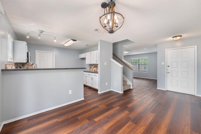 10315 Budtime Ln, Dallas, TX 75217 - kitchen featuring dark countertops, dark wood finished floors, a chandelier, white cabinetry, and baseboards