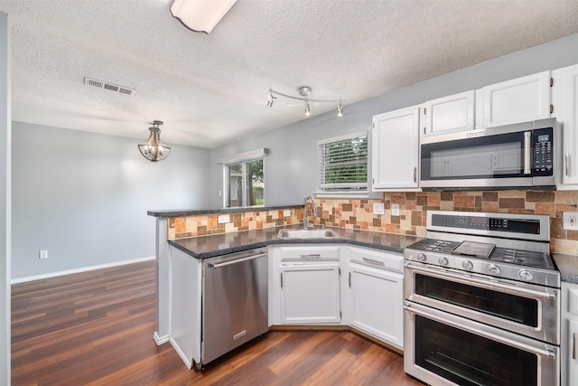 10315 Budtime Ln, Dallas, TX 75217 - kitchen with stainless steel appliances, a sink, a peninsula, dark wood-style floors, and backsplash