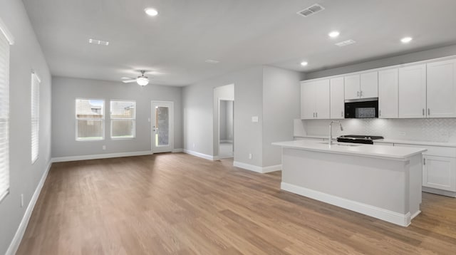516 Willet Dr, Mckinney, TX 75069 - kitchen featuring stainless steel microwave, light countertops, backsplash, light wood-style flooring, and a ceiling fan