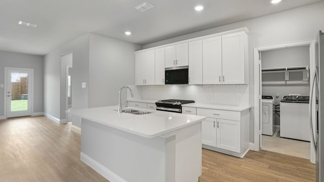 516 Willet Dr, Mckinney, TX 75069 - kitchen with stainless steel microwave, washing machine and dryer, light wood-type flooring, tasteful backsplash, and gas range oven