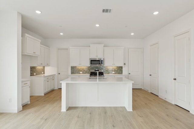 15792 Millwood Trl, Frisco, TX 75033 - kitchen featuring appliances with stainless steel finishes, backsplash, light wood finished floors, light countertops, and white cabinetry