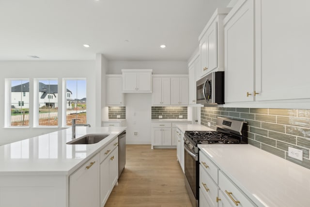 15792 Millwood Trl, Frisco, TX 75033 - kitchen featuring stainless steel appliances, a sink, decorative backsplash, light wood finished floors, and white cabinets