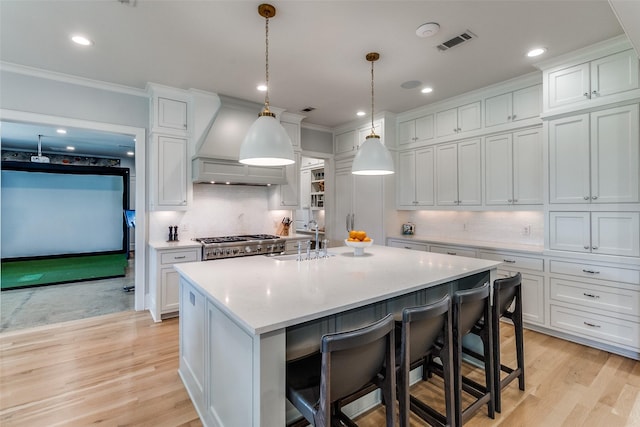 3970 Cobblestone Cir, Dallas, TX 75229 - kitchen featuring a sink, crown molding, decorative backsplash, light wood-type flooring, and a center island with sink