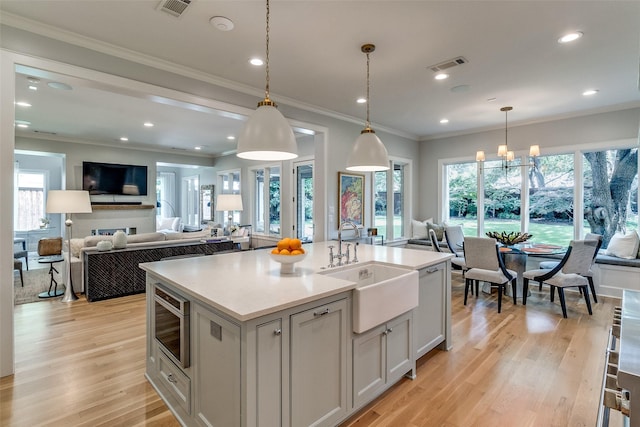 3970 Cobblestone Cir, Dallas, TX 75229 - kitchen with open floor plan, a sink, a center island with sink, light countertops, and light wood-style floors