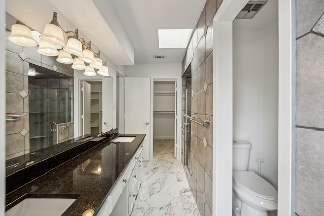 2207 Oakwood Ln, Arlington, TX 76012 - full bath featuring marble look tile flooring, a walk in closet, toilet, double vanity, and a shower stall