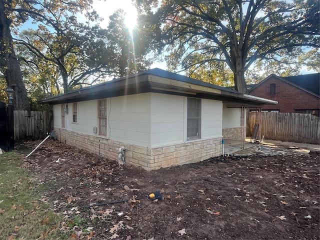 view of property exterior with fence and stone siding