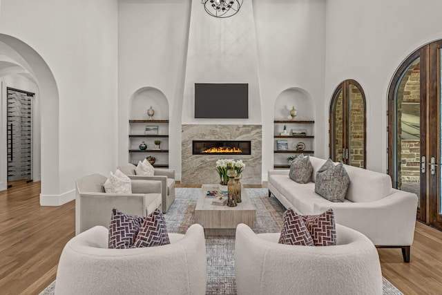 2210 Barcelona Ct, Westlake, TX 76262 - living area with built in shelves, wood finished floors, a high ceiling, baseboards, and a high end fireplace