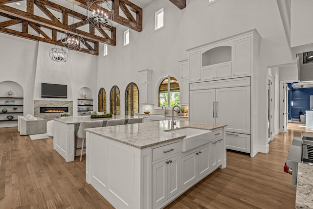 2210 Barcelona Ct, Westlake, TX 76262 - kitchen featuring a sink, a towering ceiling, a kitchen island with sink, a chandelier, and wood finished floors