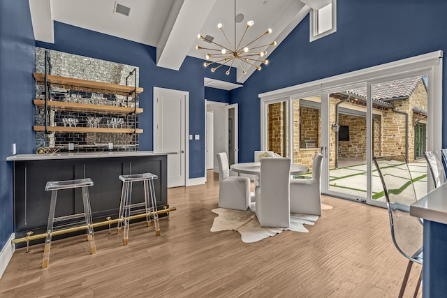 2210 Barcelona Ct, Westlake, TX 76262 - dining space with wood finished floors, bar area, a chandelier, high vaulted ceiling, and baseboards