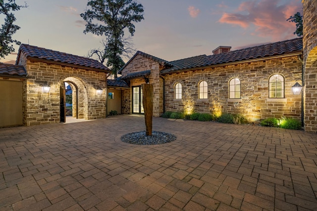 2210 Barcelona Ct, Westlake, TX 76262 - view of front facade featuring stone siding, a chimney, a tile roof, and curved driveway