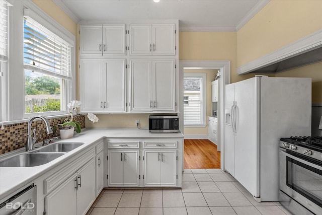 kitchen with a sink, appliances with stainless steel finishes, white cabinetry, light countertops, and light tile patterned flooring