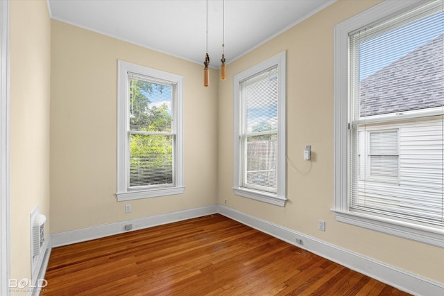 unfurnished dining area featuring ornamental molding, wood finished floors, and baseboards