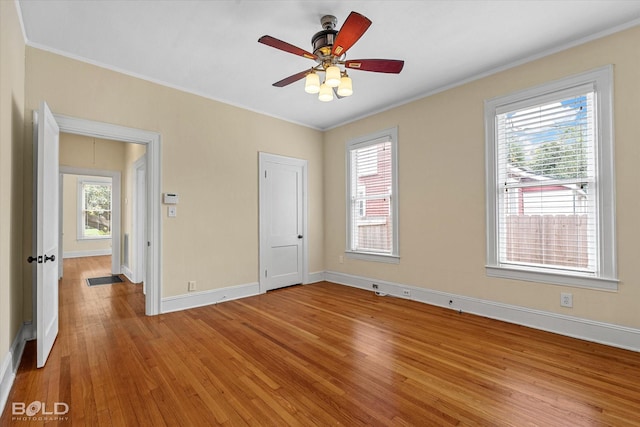 unfurnished bedroom with light wood-type flooring, ornamental molding, baseboards, attic access, and ceiling fan