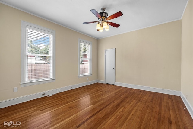 empty room with wood finished floors, ornamental molding, baseboards, and a ceiling fan