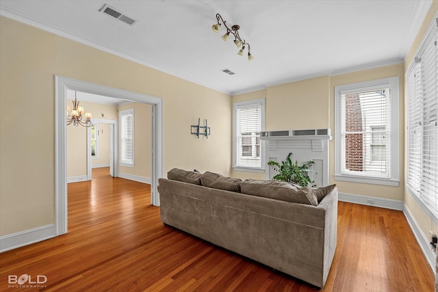 living area featuring a chandelier, hardwood / wood-style flooring, baseboards, and crown molding