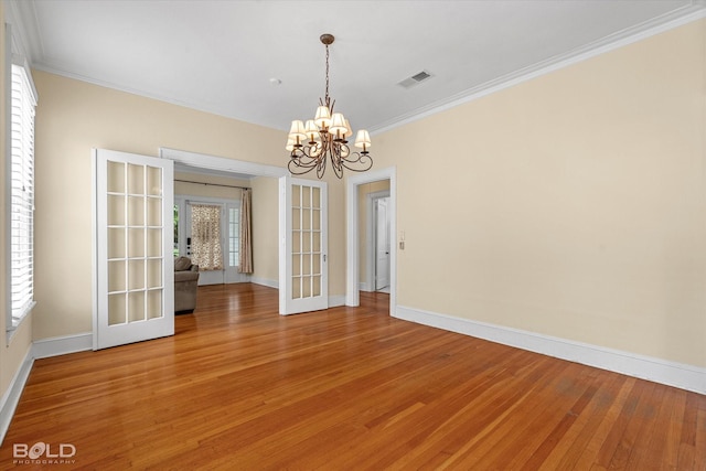 unfurnished room featuring french doors, a chandelier, crown molding, light wood finished floors, and baseboards