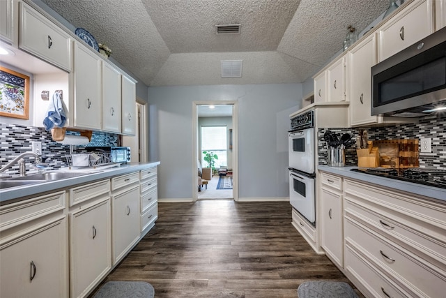 425 Headlee St, Denton, TX 76201 - kitchen featuring stainless steel microwave, white double oven, dark wood finished floors, white cabinets, and a textured ceiling