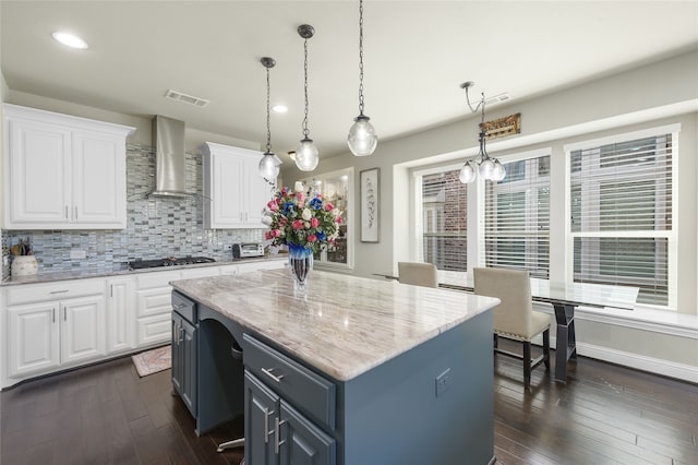 215 Dominion Dr, Wylie, TX 75098 - kitchen featuring wall chimney range hood, white cabinets, stainless steel gas stovetop, a kitchen island, and tasteful backsplash