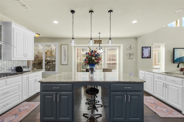 215 Dominion Dr, Wylie, TX 75098 - kitchen featuring a sink, a center island, a breakfast bar area, white cabinetry, and decorative backsplash