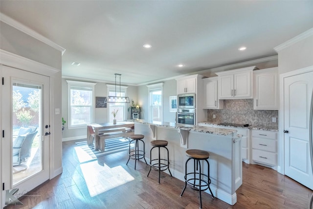 6709 Tradition Dr, Abilene, TX 79606 - kitchen featuring appliances with stainless steel finishes, plenty of natural light, crown molding, white cabinets, and a kitchen island