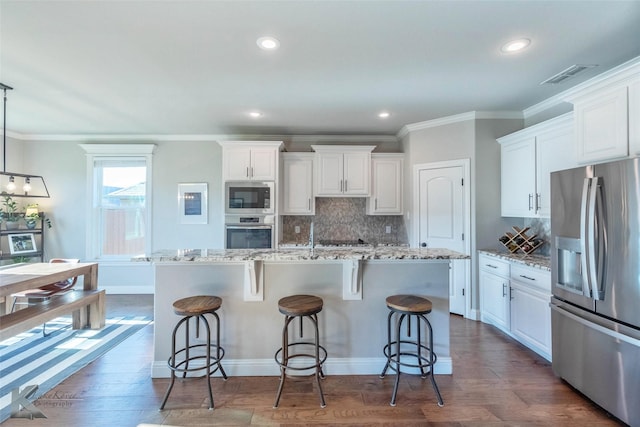 6709 Tradition Dr, Abilene, TX 79606 - kitchen featuring stainless steel appliances, tasteful backsplash, white cabinets, a kitchen island with sink, and ornamental molding