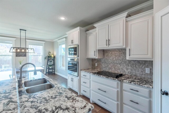 6709 Tradition Dr, Abilene, TX 79606 - kitchen featuring appliances with stainless steel finishes, a sink, white cabinetry, backsplash, and ornamental molding