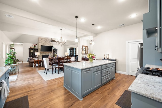 422 Sundance, Corsicana, TX 75109 - kitchen featuring a center island, a fireplace, gray cabinets, light wood-type flooring, and a chandelier
