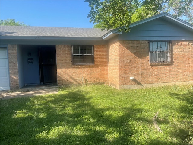 view of front of home with a front lawn, brick siding, and a shingled roof
