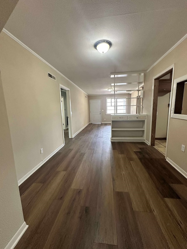 empty room with ornamental molding, dark wood-style flooring, a textured ceiling, and baseboards