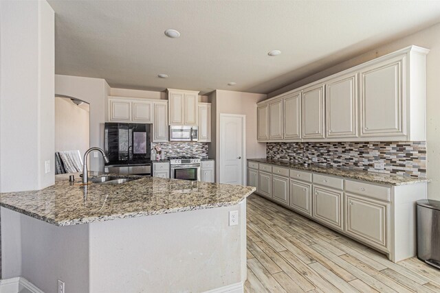 3001 Spring Ct, Midlothian, TX 76065 - kitchen with appliances with stainless steel finishes, a sink, a peninsula, light stone countertops, and decorative backsplash
