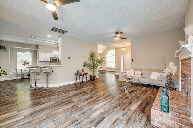 11016 Huntington Rd, Frisco, TX 75035 - living area featuring a ceiling fan, dark wood-style flooring, a textured ceiling, a brick fireplace, and baseboards