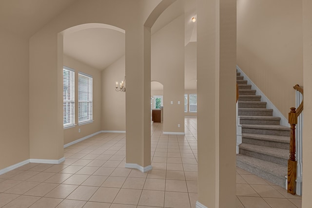 10317 Colfax Dr, Mckinney, TX 75072 - foyer with arched walkways, light tile patterned floors, high vaulted ceiling, and baseboards