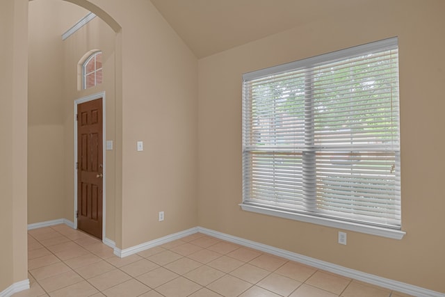 10317 Colfax Dr, Mckinney, TX 75072 - spare room featuring light tile patterned floors, vaulted ceiling, arched walkways, and baseboards