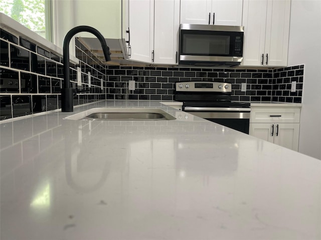 206 E Birch St, Campbell, TX 75422 - kitchen with appliances with stainless steel finishes, white cabinetry, tasteful backsplash, and a sink