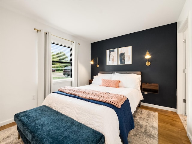 445 Melrose Dr, Richardson, TX 75080 - bedroom with light wood finished floors, an accent wall, and baseboards
