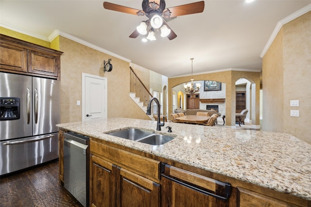 1270 Timber Ln, Frisco, TX 75036 - kitchen with stainless steel appliances, a sink, arched walkways, a large fireplace, and ornamental molding